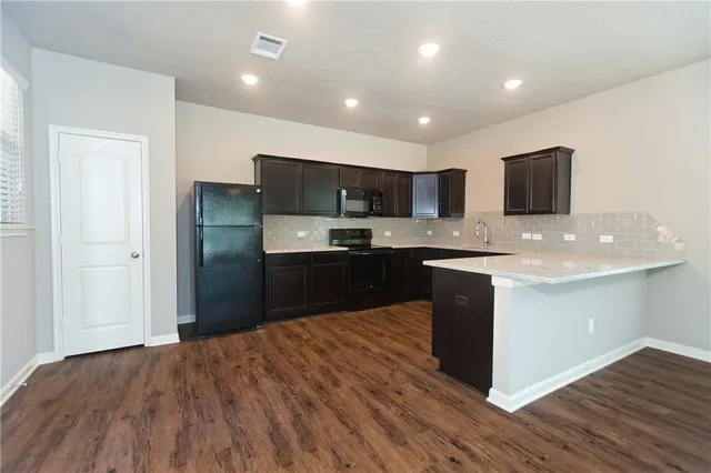 a kitchen with stainless steel appliances granite countertop a sink and a large window
