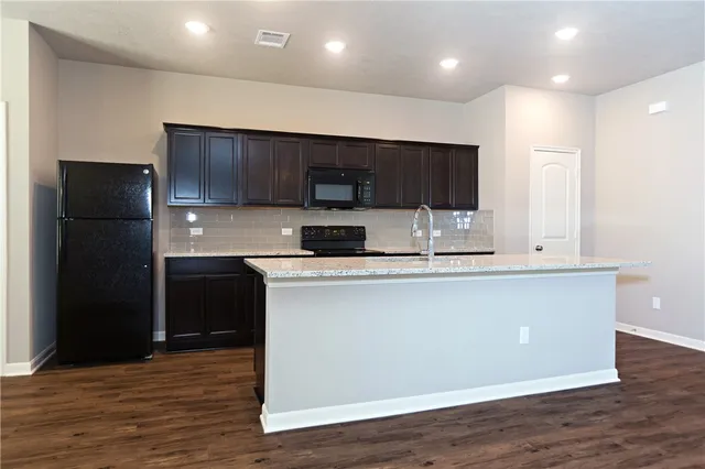 a kitchen with stainless steel appliances granite countertop a refrigerator a sink a stove a microwave and wooden floor