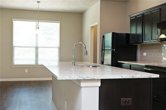 a view of kitchen with stainless steel appliances kitchen island a stove a refrigerator a sink a microwave and white cabinets with wooden floor