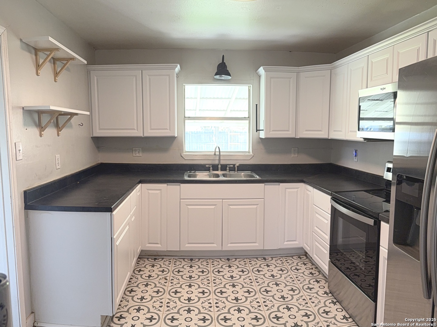 907 Dove Avenue Devine, TX 78016 - Photo 3 of 8 a kitchen with granite countertop a sink a stove a refrigerator and cabinets