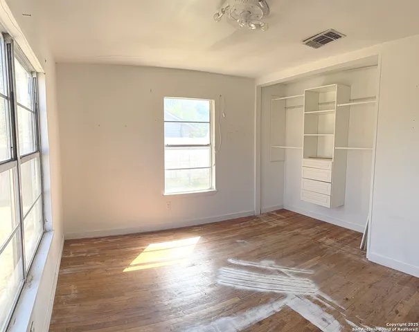 an empty room with wooden floor and windows