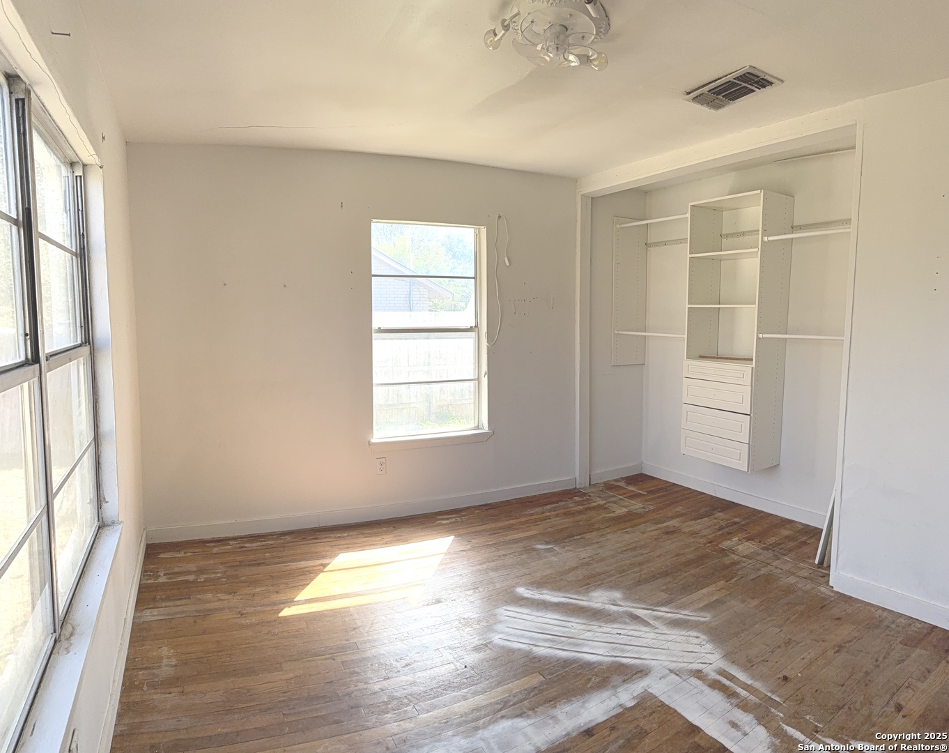 907 Dove Avenue Devine, TX 78016 - Photo 7 of 8 an empty room with wooden floor and windows