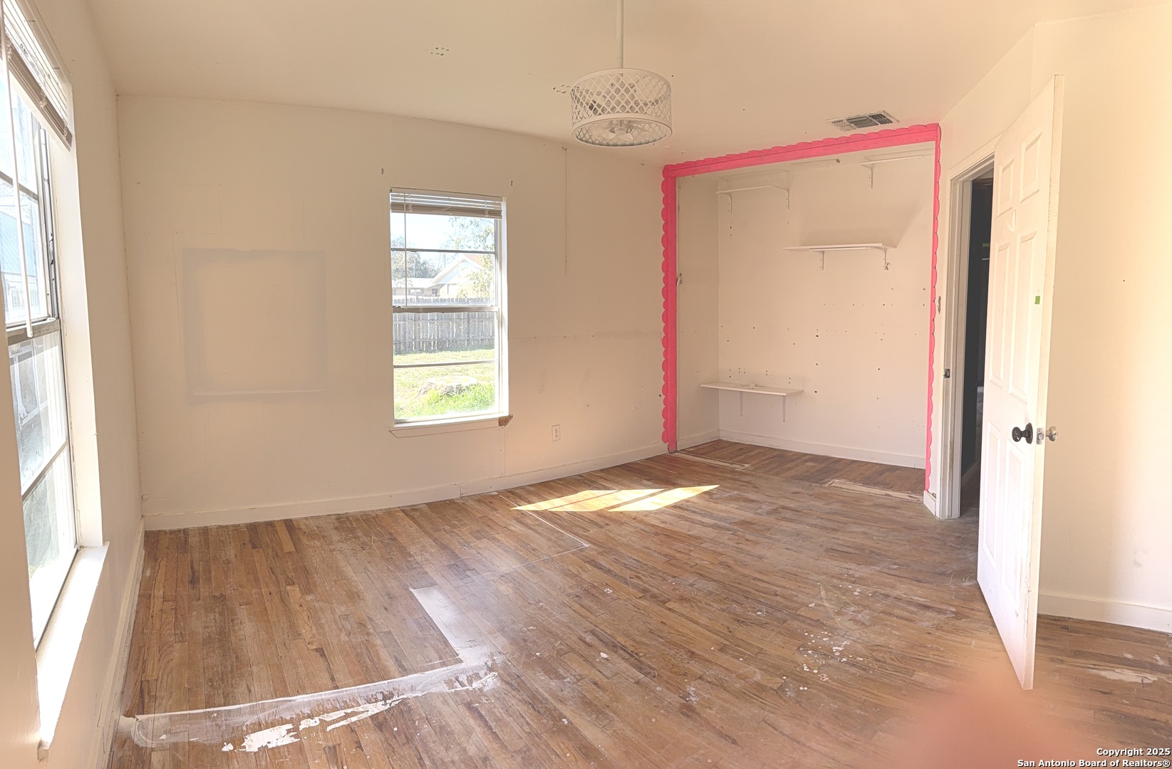 907 Dove Avenue Devine, TX 78016 - Photo 8 of 8 an empty room with wooden floor and windows