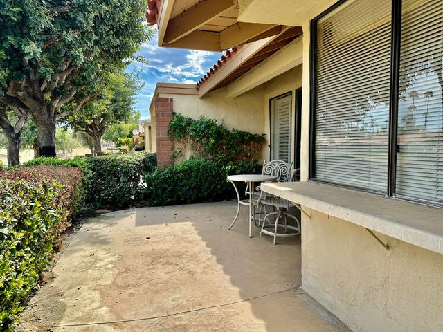 a patio with table and chairs and potted plants