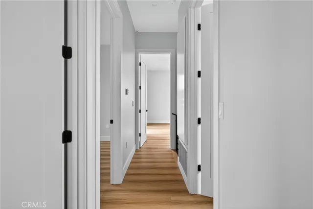 a view of a hallway with wooden floor and a bathroom