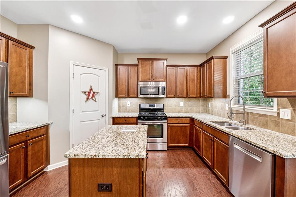 2770 Lansing Lane Cumming, GA 30041 - Photo 15 of 49 a kitchen with stainless steel appliances granite countertop wooden cabinets and a stove top oven