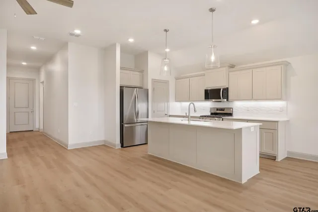 a large white kitchen with a refrigerator a sink dishwasher and a stove with wooden floor