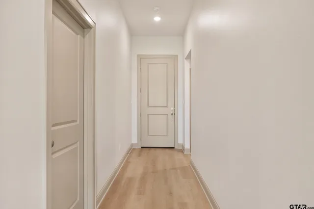 an empty room with wooden floor chandelier fan and windows