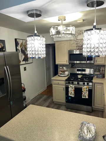 a kitchen with stainless steel appliances kitchen island granite countertop a stove a refrigerator a sink a dining table and chairs with wooden floor