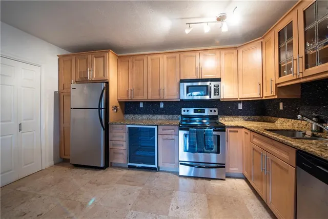 a kitchen with stainless steel appliances granite countertop a refrigerator stove a sink and dishwasher
