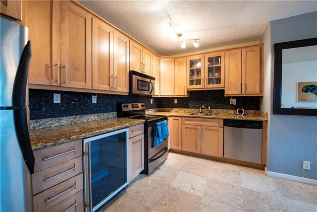 a kitchen with stainless steel appliances granite countertop a stove a sink dishwasher and a microwave oven with cabinets