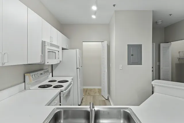 a room with stainless steel appliances a refrigerator a sink a stove and white cabinets