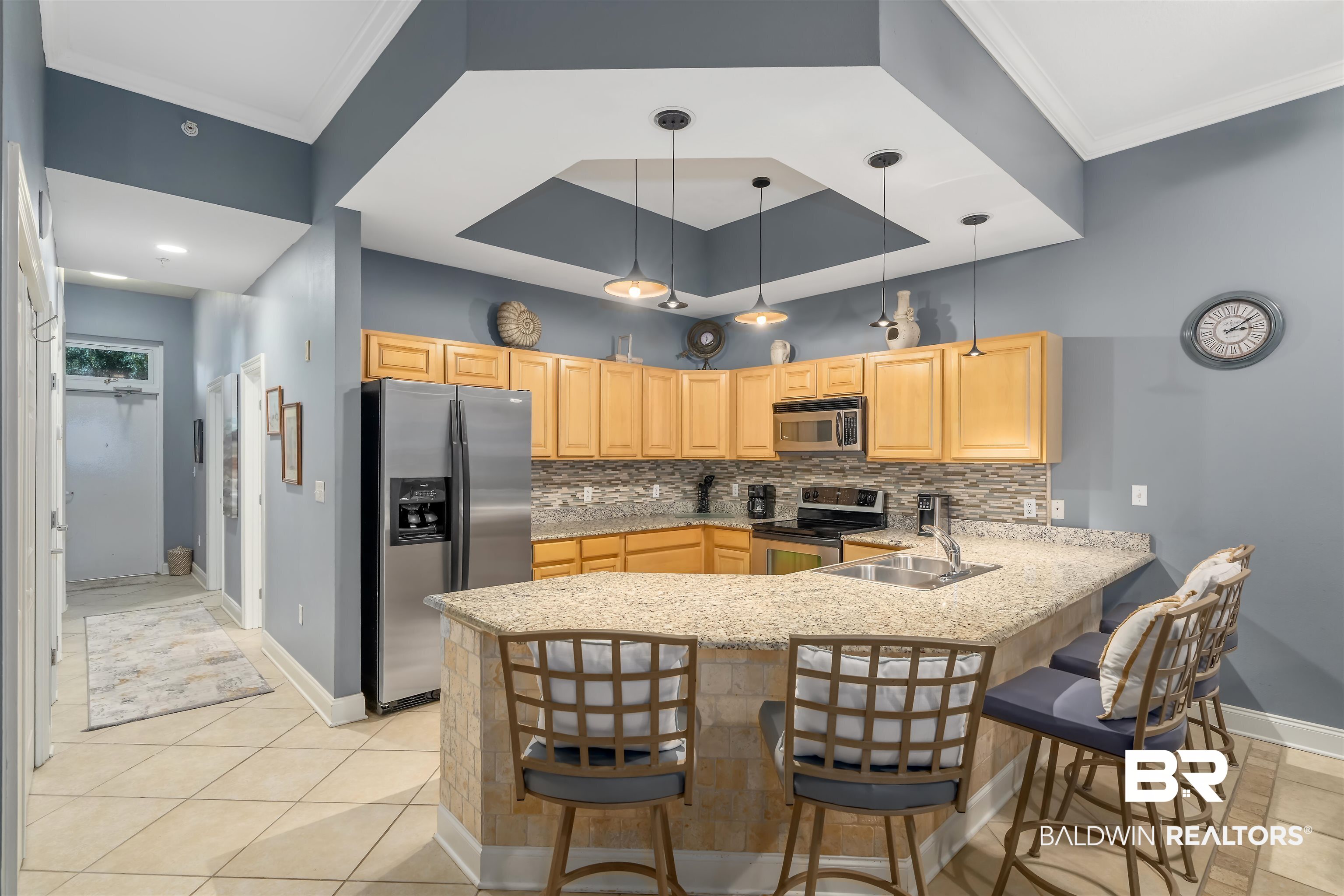 27800 Canal Road, Unit 113 Orange Beach, AL 36561 - Photo 12 of 35 Kitchen with appliances with stainless steel finishes, a peninsula, a breakfast bar area, hanging light fixtures, and light tile patterned floors