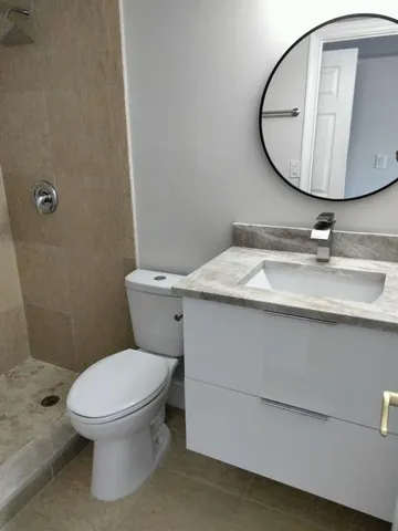 a bathroom with a granite countertop toilet sink mirror and vanity