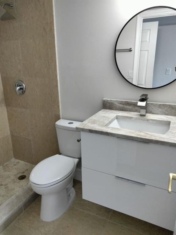 1100 Crystal Lake Drive, Unit 115 Deerfield Beach, FL 33073 - Photo 4 of 11 a bathroom with a granite countertop toilet sink mirror and vanity