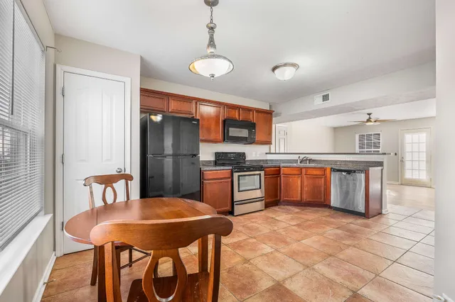 a kitchen with stainless steel appliances granite countertop a stove a sink a refrigerator dining table and chairs