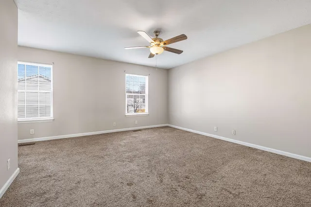 an empty room with windows and fan
