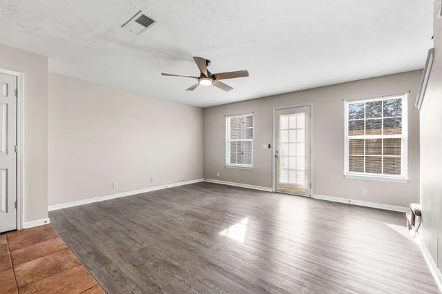 an empty room with wooden floor and windows