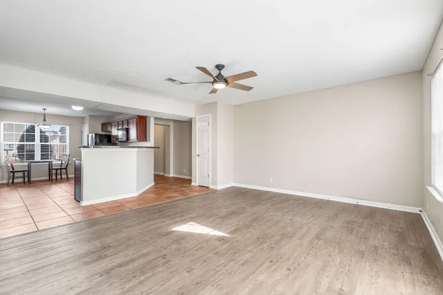 an empty room with wooden floor and a ceiling fan