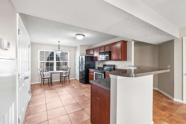 a kitchen with stainless steel appliances granite countertop a stove top oven a sink a dining table and chairs