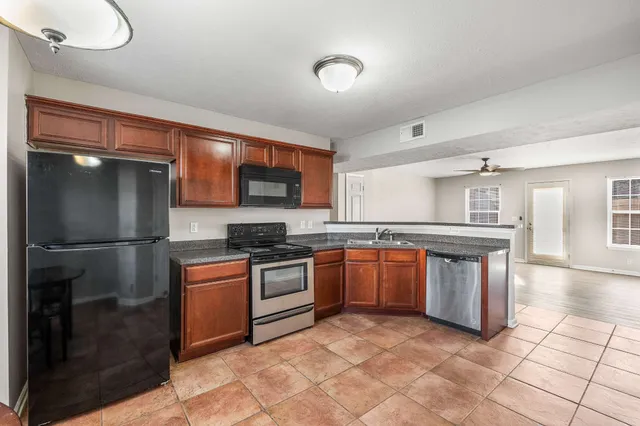 a kitchen with stainless steel appliances granite countertop a stove top oven a sink and a refrigerator