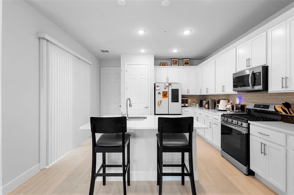 269 Platform Lane DeBary, FL 32713 - Photo 16 of 41 a kitchen with stainless steel appliances granite countertop a stove a sink a microwave a refrigerator white cabinets and wooden floor