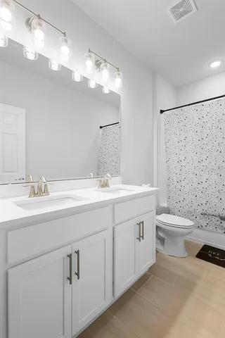 a bathroom with a double vanity sink toilet and a mirror