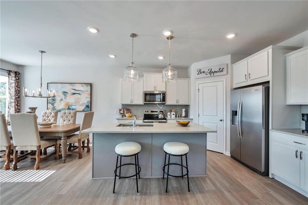 156 Millers Lane Calhoun, GA 30701 - Photo 6 of 26 a kitchen with stainless steel appliances granite countertop a dining table chairs refrigerator and sink