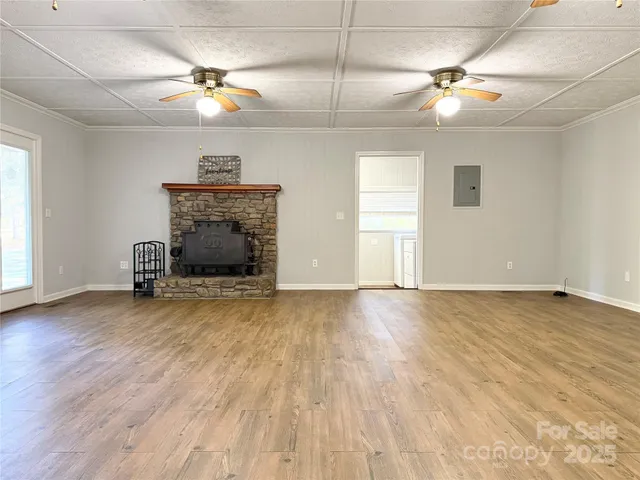 an empty room with wooden floor chandelier fan and windows