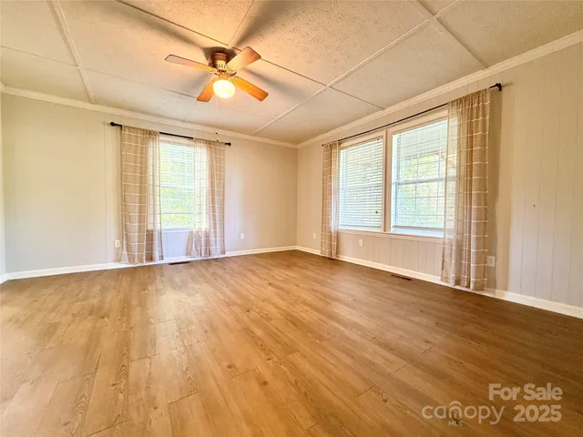 a view of an empty room with a window and wooden floor