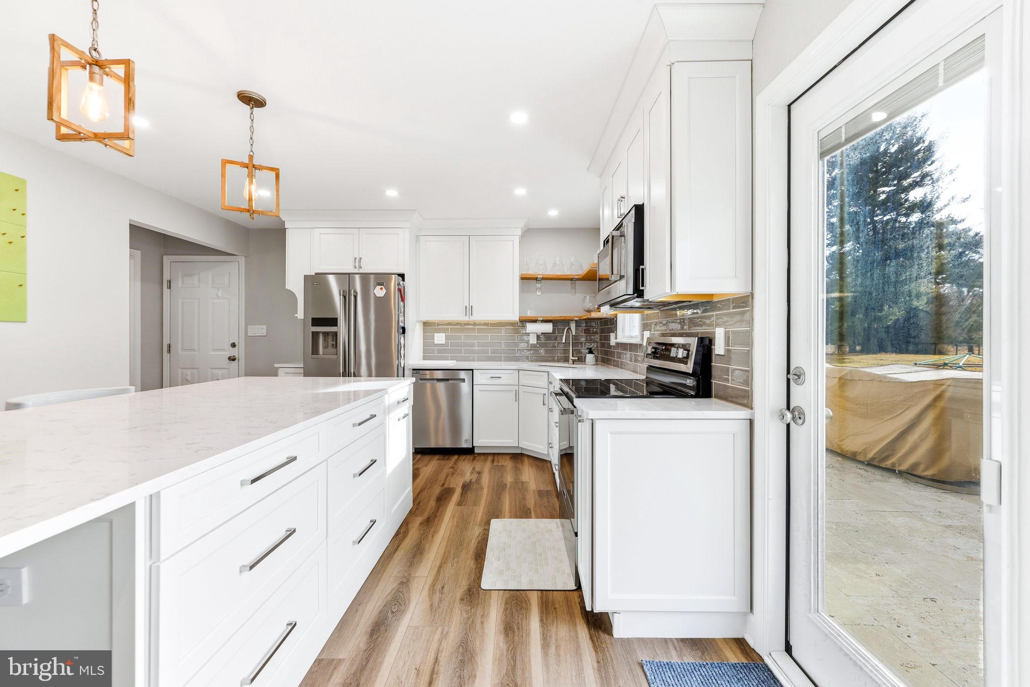 16932 Flickerwood Road Parkton, MD 21120 - Photo 14 of 64 a kitchen with white cabinets a sink dishwasher and a stove with wooden floor