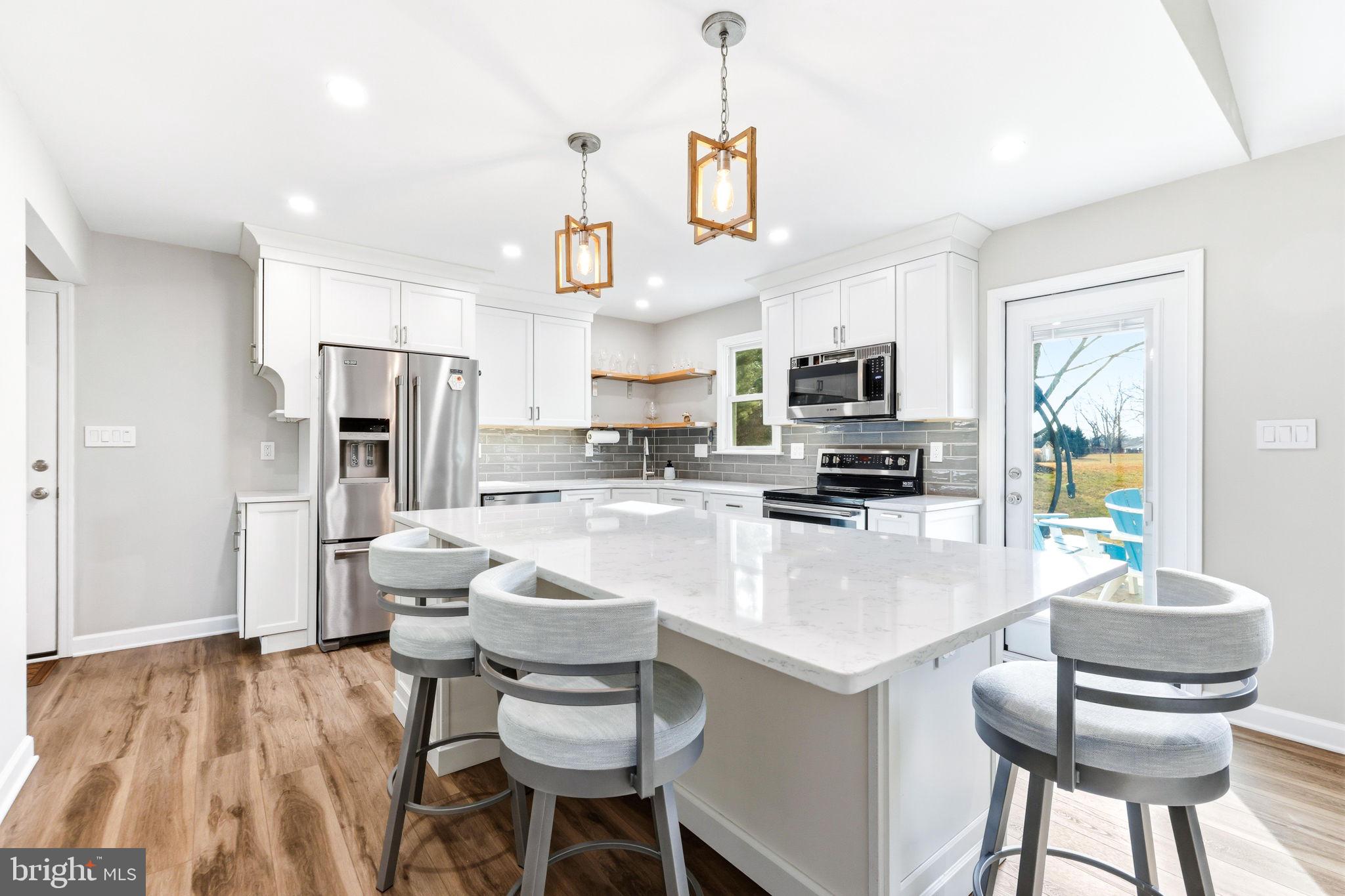 16932 Flickerwood Road Parkton, MD 21120 - Photo 2 of 64 a kitchen with stainless steel appliances kitchen island granite countertop a refrigerator a stove a sink a dining table and chairs with wooden floor