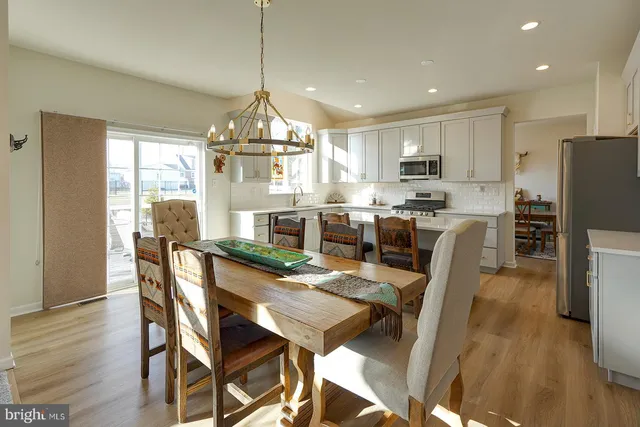a dining room with stainless steel appliances kitchen island granite countertop a table chairs and a refrigerator