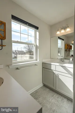 a large bathroom with a window sink and cabinets
