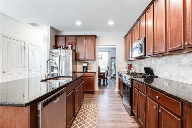a kitchen with stainless steel appliances granite countertop a refrigerator a stove and white cabinets