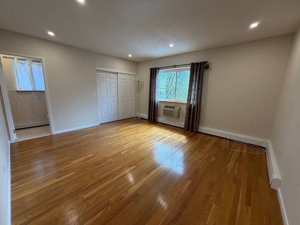 383 Langley Road, Unit 11 Newton, MA 02459 - Photo 7 of 15 an empty room with wooden floor and windows