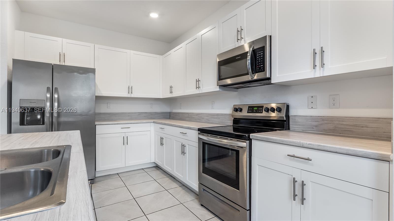 13410 Southwest 287th Terrace Homestead, FL 33033 - Photo 12 of 32 a kitchen with granite countertop white cabinets stainless steel appliances and sink