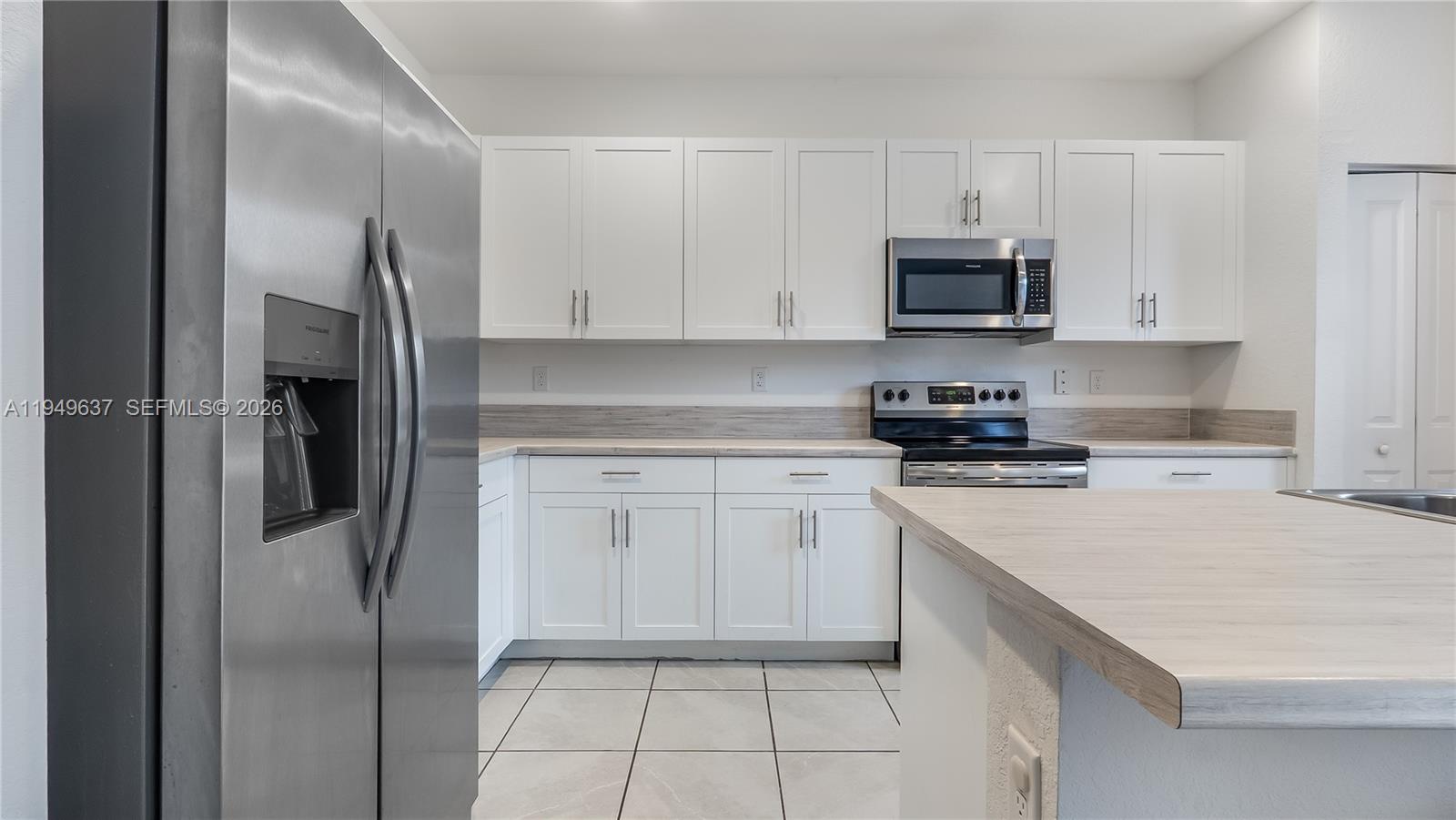 13410 Southwest 287th Terrace Homestead, FL 33033 - Photo 13 of 32 a kitchen with stainless steel appliances granite countertop a refrigerator sink and white cabinets