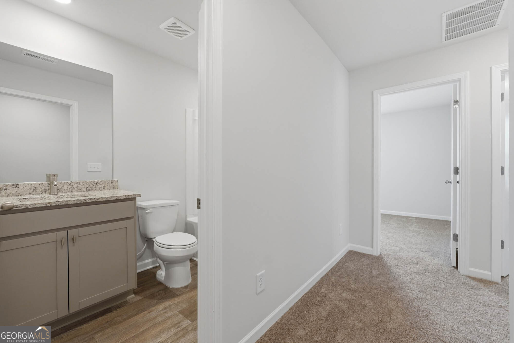 5284 Magnolia Grove Way Gainesville, GA 30504 - Photo 15 of 31 a bathroom with a granite countertop toilet a sink and a mirror