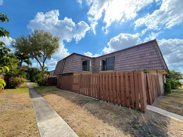 a backyard of a house with large trees and wooden fence