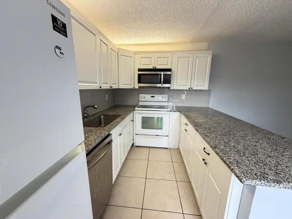 a white kitchen with granite top