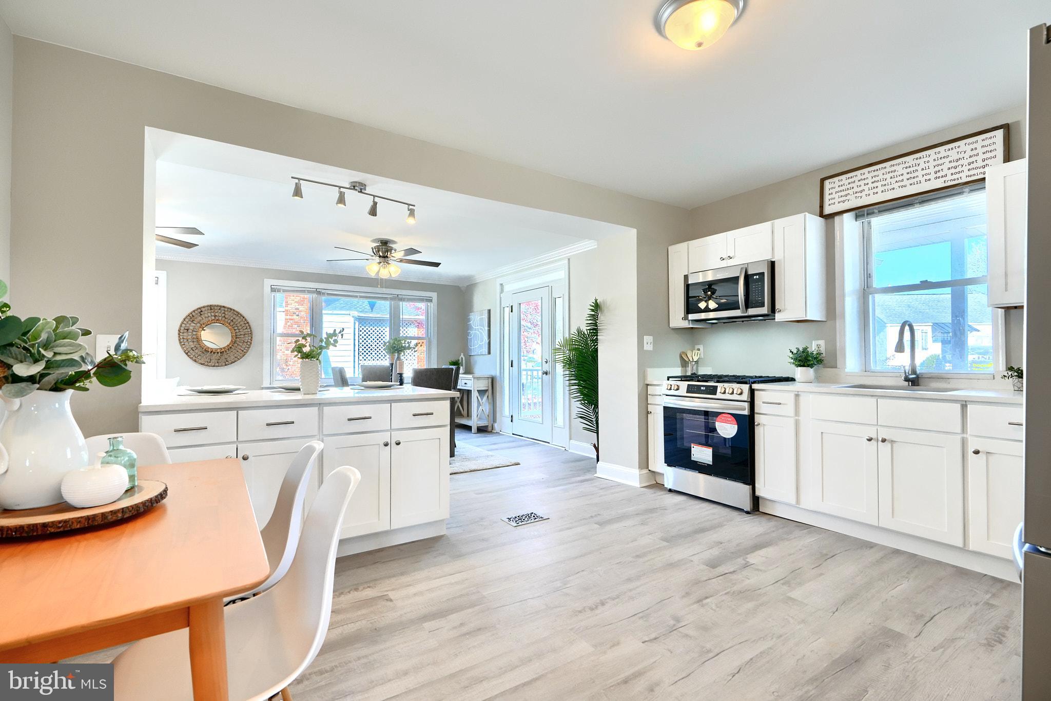 235 Pinewood Road Dundalk, MD 21222 - Photo 57 of 59 a kitchen with stainless steel appliances granite countertop a stove top oven a sink a dining table and chairs with wooden floor
