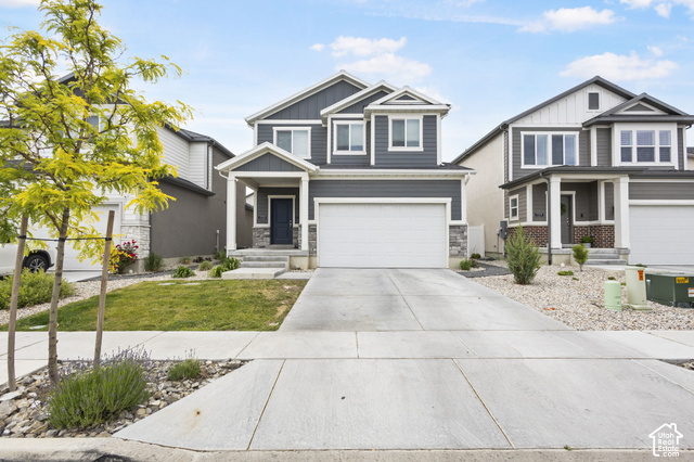 7723 Conger Road Magna, UT 84044 - Photo 20 of 24 Two-story exterior with dark gray siding, white trim, stone accents, a covered front porch, and an attached two-car garage