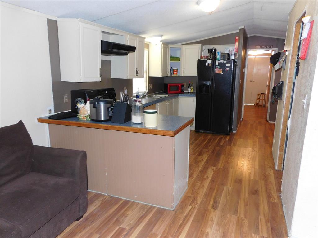 233 HCR 3315 Hubbard, TX 76648 - Photo 24 of 31 a kitchen with granite countertop a refrigerator a sink dishwasher and wooden cabinets with wooden floor