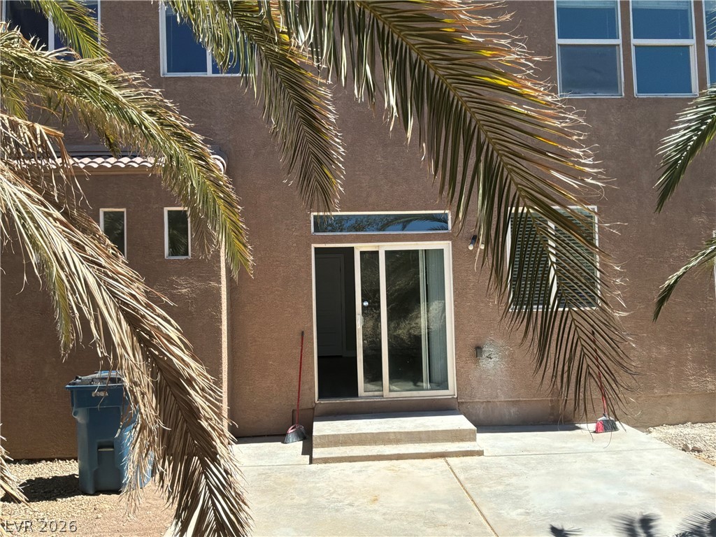 9041 Rendon Street Las Vegas, NV 89143 - Photo 32 of 34 Sliding glass doors open directly to a concrete patio bordered by mature palm trees.