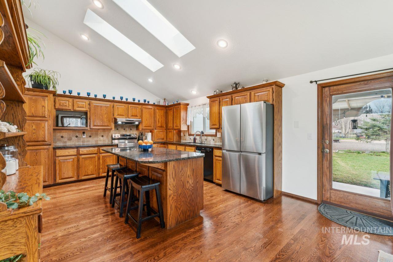 710 Keogh Lane Caldwell, ID 83607 - Photo 16 of 50 Kitchen with a skylight, wood finish cabinets, black appliances, backsplash, and vaulted ceiling