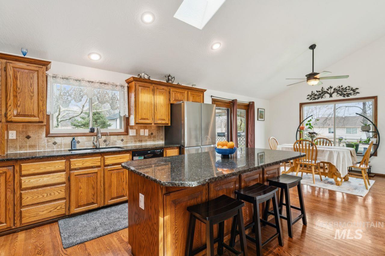 710 Keogh Lane Caldwell, ID 83607 - Photo 18 of 50 Kitchen with wood finish cabinets, a skylight, light wood-style floors, decorative backsplash, and vaulted ceiling