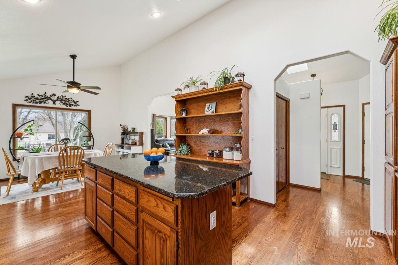 710 Keogh Lane Caldwell, ID 83607 - Photo 21 of 50 Kitchen featuring arched walkways, a kitchen island, light wood finished floors, dark stone countertops, and wood finish cabinetry