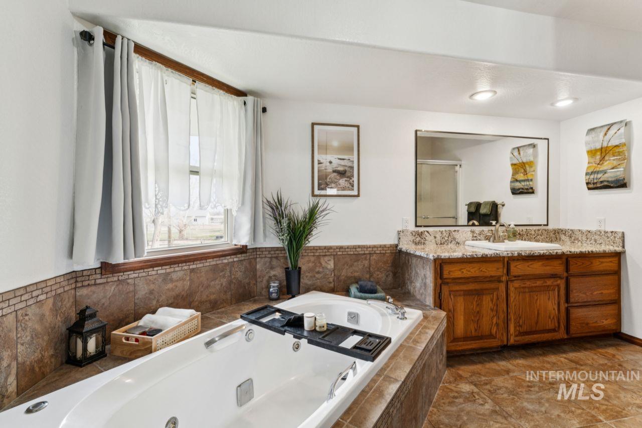 710 Keogh Lane Caldwell, ID 83607 - Photo 26 of 50 Bathroom featuring vanity, a tub with jets, and a shower stall
