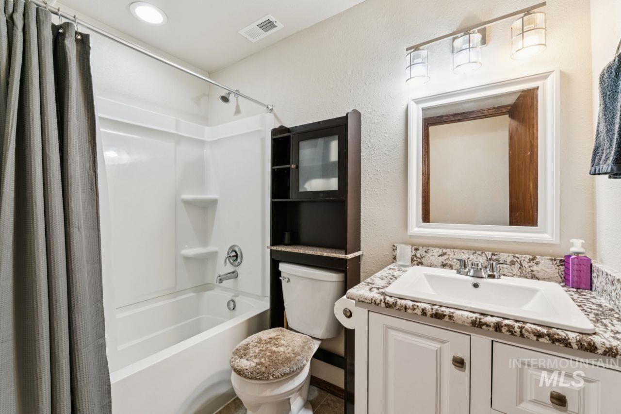 710 Keogh Lane Caldwell, ID 83607 - Photo 30 of 50 Bathroom featuring a textured wall, vanity, and shower / bathtub combination with curtain
